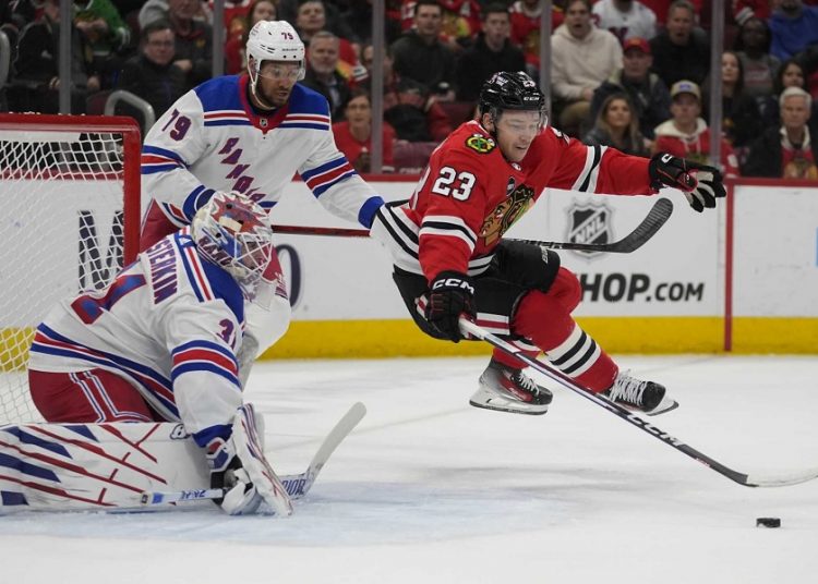 Chicago Blackhawks Philipp Kurashev (23) trips and loses the puck in front of New York Rangers goaltender Igor Shesterkin during their NHL hockey game in Chicago.