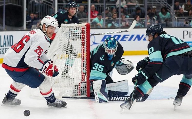 Washington Capitals Nic Dowd (L) goes for the puck as Seattle Kraken goaltender Joey Daccord (C) and Matty Beniers defend during their NHL game in Seattle.
