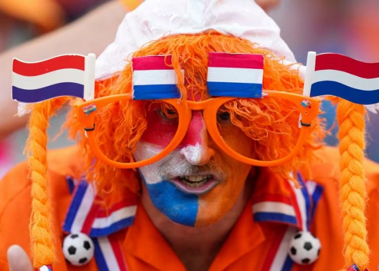 A fan of the Dutch soccer team poses for photos prior to a Group D match between Poland and the Netherlands at the Euro 2024 in Hamburg, Germany.