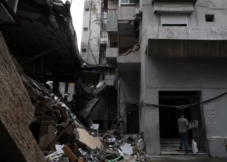 A man carries a ladder next to a damaged building in the aftermath of an Israeli strike in central Beirut, targeting what Israel said is a Hezbollah-affiliated bank, following an escalation between Hezbollah and Israel amid the US-Israeli conflict with Iran, in Beirut, Lebanon, March 15, 2026. REUTERS