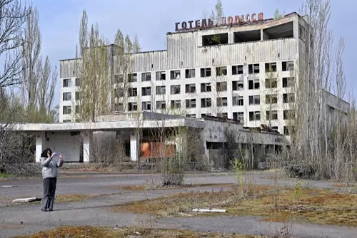 Chernobyl, 40 years since disaster: Five things to know 11 - Egyptian Gazette A visitor takes a picture in front of abandoned hotel in the ghost city of Pripyat near Chernobyl Nuclear Power Plant on April 23, 2026. AFP PHOTO