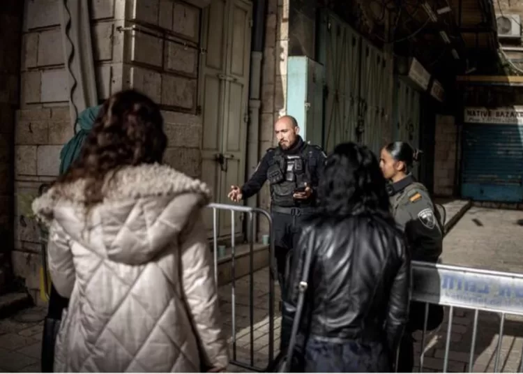 An Israeli policeman (C) explains from behind a security barrier to a group of Orthodox Christian pilgrims that they are not allowed to the Church of the Holy Sepulchre, where the Latin Patriarch of Jerusalem will celebrate Easter Sunday Mass, behind closed doors due to the ongoing war, in the old city of Jerusalem on April 5, 2026. (AFP)
