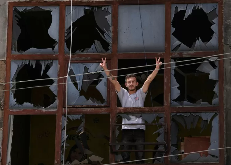 A man flashes the victory sign through the shattered window of a damaged apartment following a ceasefire between Israel and Hizbollah in the town of Nabatiyeh, southern Lebanon. AP