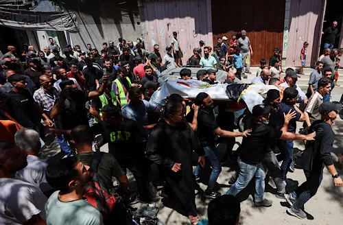 Mourners carry the body of Palestinian man Mohammad al-Waheidi, who worked for the Egyptian Relief Committee and was killed in an Israeli strike on Tuesday, during his funeral, in Gaza City