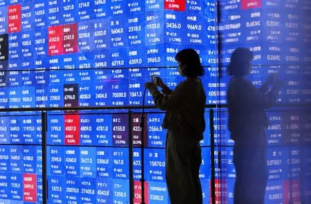 Oil price surge reignites inflation worries 12 - Egyptian Gazette FILE PHOTO: A visitor stands next to an electronic screen displaying Japan's Nikkei stock prices quotation board inside a conference hall in Tokyo, Japan March 4, 2026. REUTERS/Issei Kato/File Photo