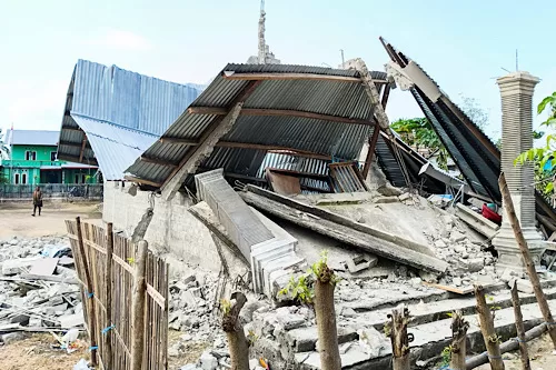 A person walks near a heavily-damaged house after an earthquake felt in Nanga Mbaur village, East Manggarai, East Nusa Tenggara province, Indonesia, August 16, 2026. REUTERS/Gabrin Anggur Purchase Licensing Rights