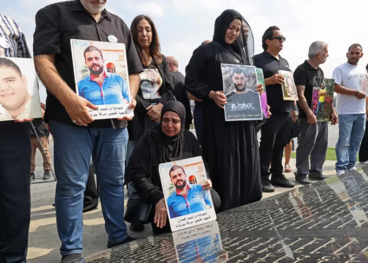 Family members carry the portraits of the victims of 2020 Beirut port blast as they gather around the marble memorial engraved with the names of the victims near the blast's ground zero © Anwar AMRO / AFP