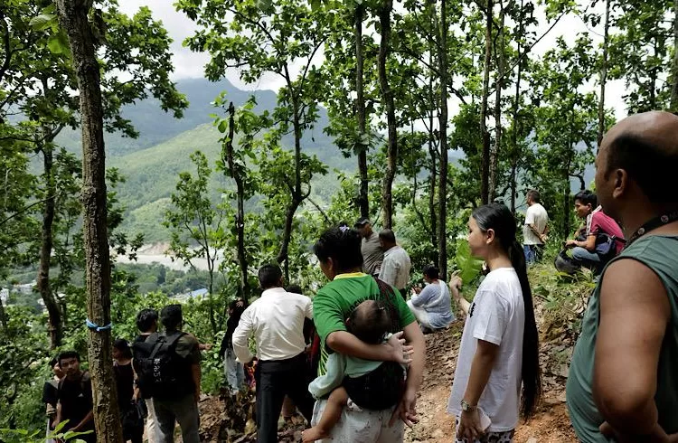 People stand on a hill after reaching high ground following a warning that a lake has broken its banks, two days after flash floods and a mudslide in Trishuli, Nuwakot district, Nepal, August 28, 2026. REUTERS/