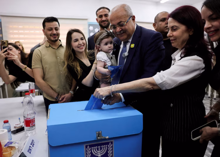 [1/3]Palestinian candidate Ahmad Tibi of the Joint List party with his family votes during the national election, in the Arab village of Taibe, northern Israel, October 27, 2026. REUTERS/Ammar Awad
