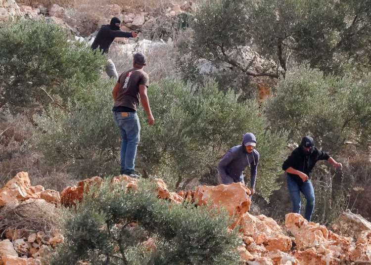 An Israeli settler points a gun amid clashes with Palestinians harvesting olives in Abu Falah near Ramallah in the Israeli-occupied West Bank, October 16, 2026. REUTERS