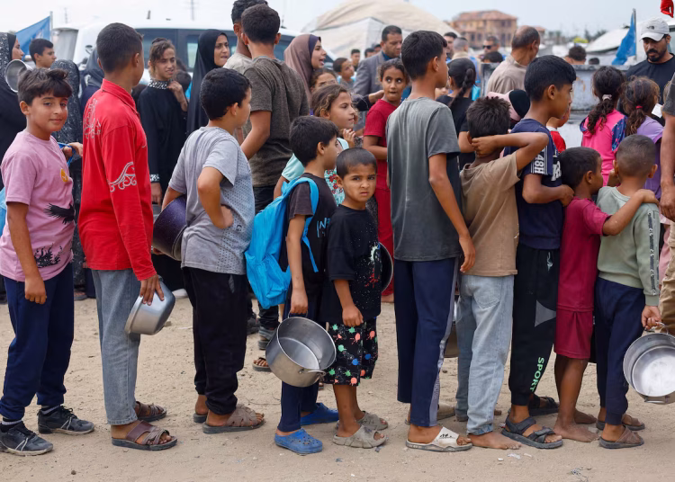 Palestinian children wait to receive food from a soup kitchen funded by the World Food Programme (WFP), in Deir Al-Balah, in the central Gaza Strip October 18, 2026.